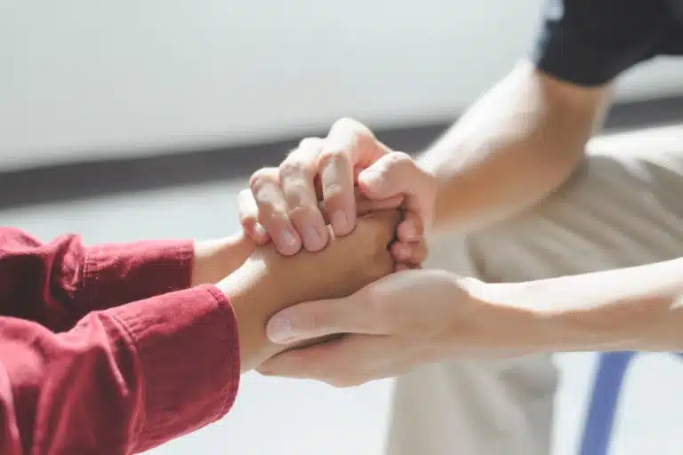 A close-up image of two individuals holding hands, symbolizing compassion, support, and emotional connection, often associated with care, empathy, and understanding in challenging times.