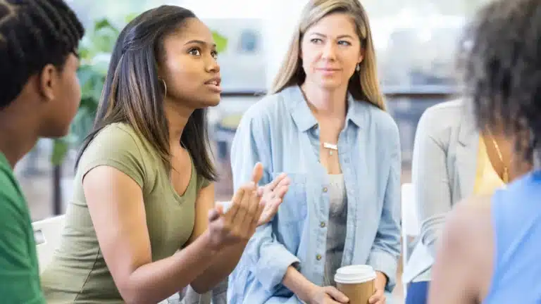 Focused group discussion with diverse women sharing experiences and support in a welcoming and collaborative environment.