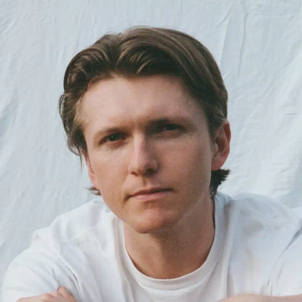 Close-up portrait of a thoughtful Lukas Wagner in a white shirt against a soft, light background.