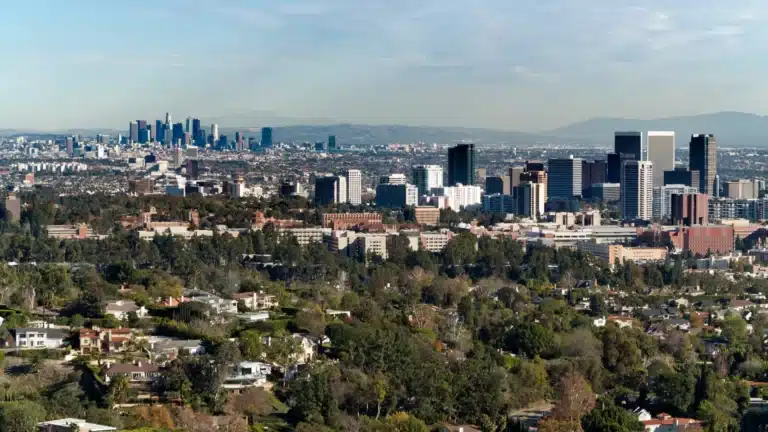 Aerial view of Los Angeles, California, showing the downtown skyline, surrounding buildings, and greenery in the foreground.